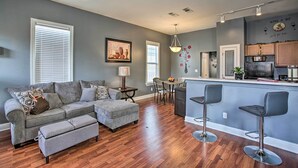 Una sala moderna con un sofá gris, un reposapiés y una zona de comedor con una mesa y sillas.