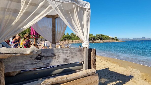 A beachside wooden structure with a canopy, overlooking a sandy beach and the sea.