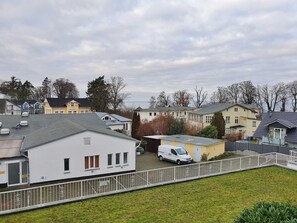 A residential area with houses, a white van, and a fenced parking area.