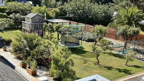 Ein Wohngebiet mit eingezäuntem Garten, einem Trampolin und einer kleinen Holzkonstruktion.