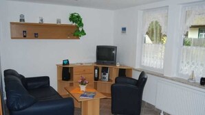 Ein Wohnzimmer mit einer Couch, einem Couchtisch, einem Fernseher und einem Bücherregal.