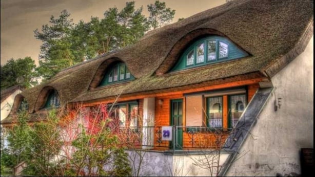 Eine Reihe traditioneller Häuser mit Strohdächern und Holzbalkonen.