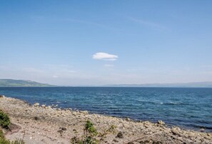 A rocky shoreline with calm sea and distant hills.