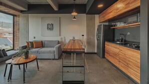 Een moderne keuken met houten kastjes, een roestvrijstalen koelkast, en een eethoek met een houten tafel en stoelen.