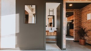 Een modern interieur met een bakstenen muur, een houten toonbank en een witte wastafel.