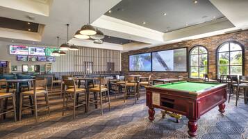 A billiards room with tables, chairs, and a pool table.