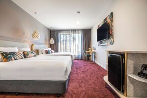 A hotel room with two beds, a TV, a fireplace, and a desk with a lamp. - Nightelier Carrum Downs Sands Hotel (Carrum Downs)