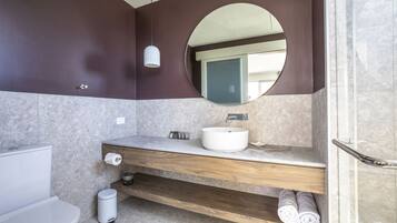 A modern bathroom with a wooden vanity, a round mirror, and a white sink.