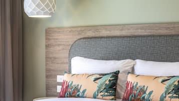 Una cama bien hecha con dos almohadas, cabecera de madera y una lámpara colgante.