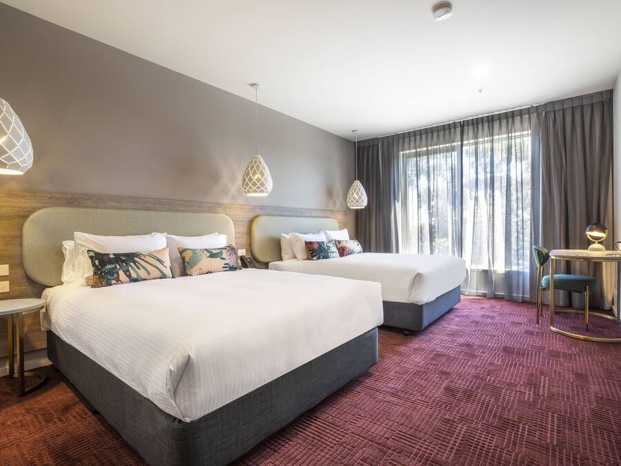 Habitación de hotel con dos camas, una mesita, una silla y un televisor.