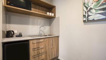 A compact kitchen with a microwave, coffee maker, and sink.