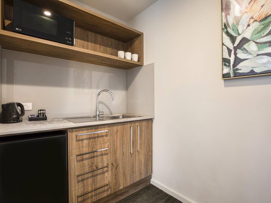 A compact kitchen with a microwave, coffee maker, and sink.