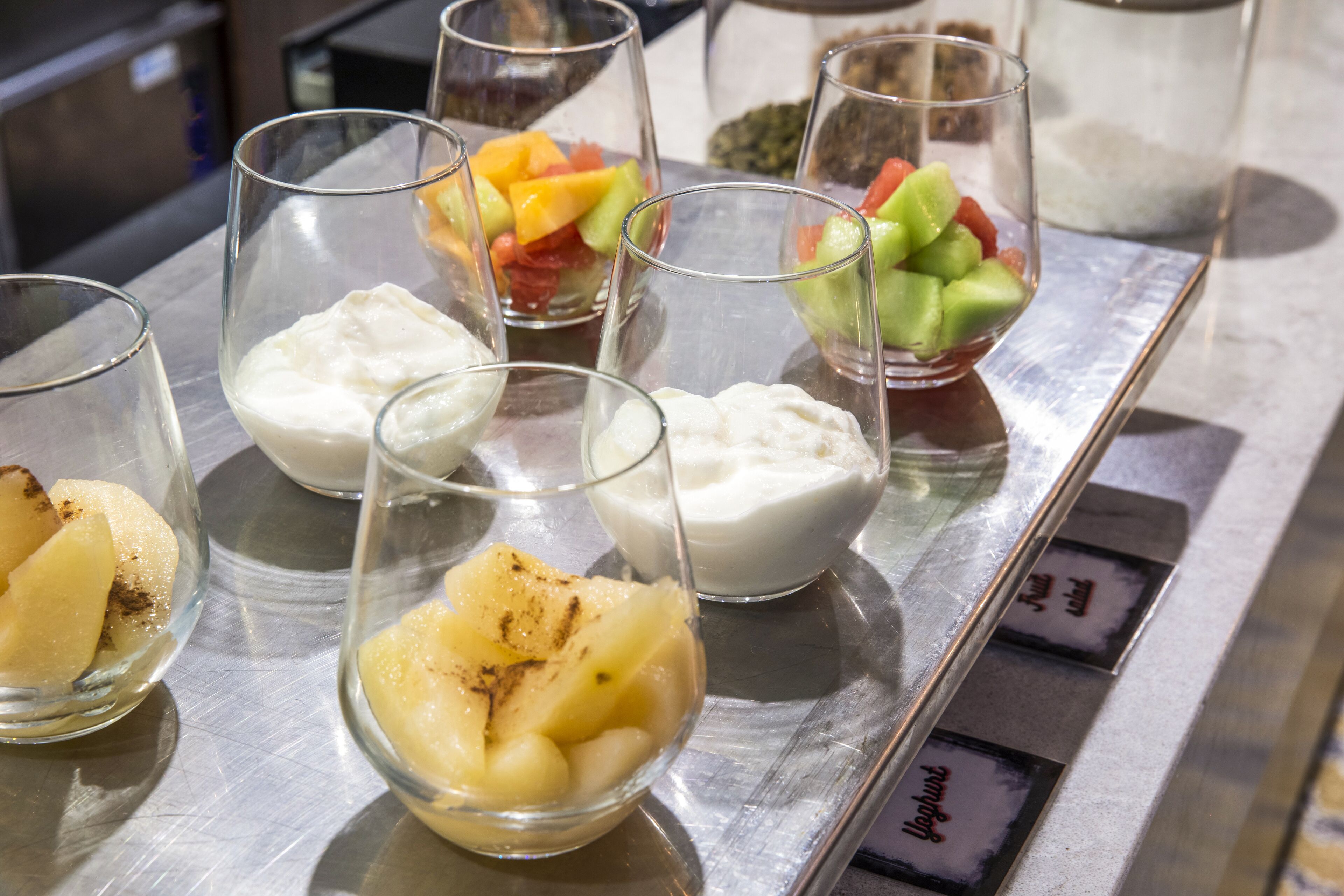 A selection of desserts in clear glass bowls on a metallic tray.