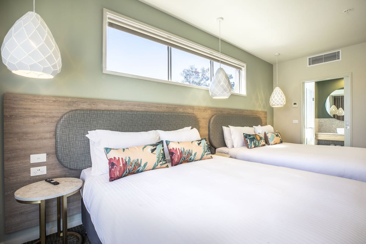 Ein Hotelzimmer mit zwei Betten, einem runden Tisch und Pendelleuchten.