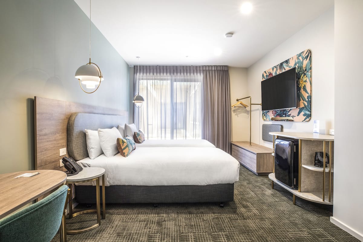 Ein Hotelzimmer mit einem großen Bett, einem Schreibtisch mit Telefon, einem Fernseher und einer Kaffeemaschine.