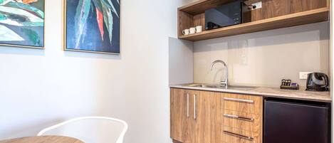 Una cucina compatta con mobili in legno, un lavello e un forno a microonde su un ripiano.