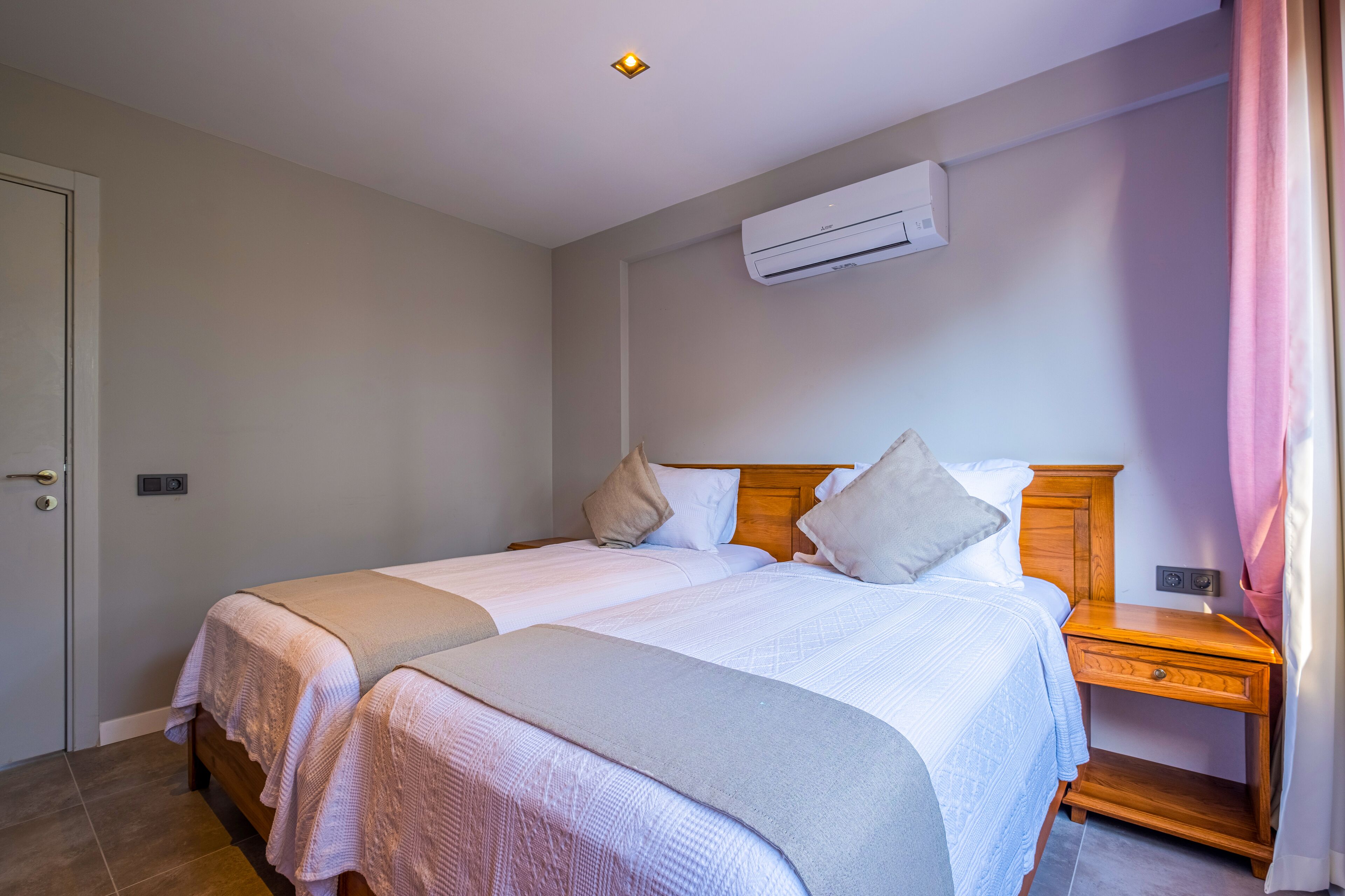 Una cama doble con cabecera de madera, una mesita de noche y un equipo de aire acondicionado en la pared.