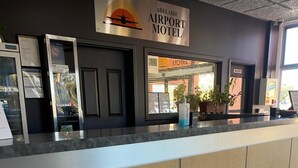 A reception desk at Adelaide Airport Motel with a sign above indicating the location.