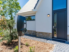Experience a contemporary building with a clean design, featuring a black electric vehicle charging station and a welcoming entrance.