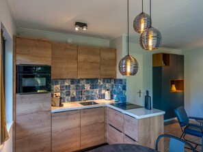 Une cuisine moderne avec des meubles en bois, un pare-feu en carrelage et des luminaires suspendus.