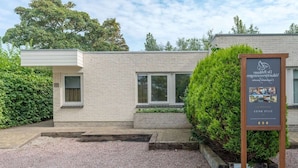 Un bâtiment moderne avec une façade en briques, de grandes fenêtres et une allée gravillonnée.