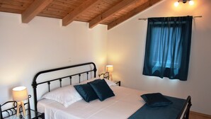 Ein Schlafzimmer mit einem Bett, Nachttischen, Lampen und einem Fenster mit Vorhängen.
