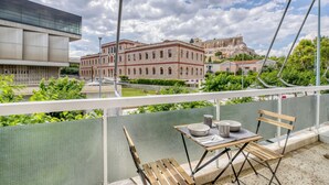 En balkon med et bord, stole og udsigt til historiske bygninger og en fæstning.