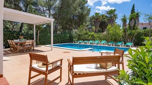 Uma área de piscina com pergolado, espreguiçadeiras e conjunto de jantar.