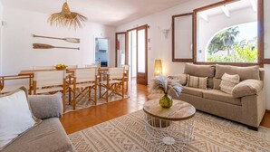 Uma sala ampla com conjunto de jantar, sofá, mesa de centro e uma janela grande com vista para o verde.