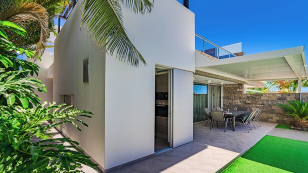 Una casa moderna con un patio, un comedor y un muro de piedra.