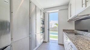 Una cocina moderna con electrodomésticos de acero inoxidable, encimera de granito y vista a una piscina.