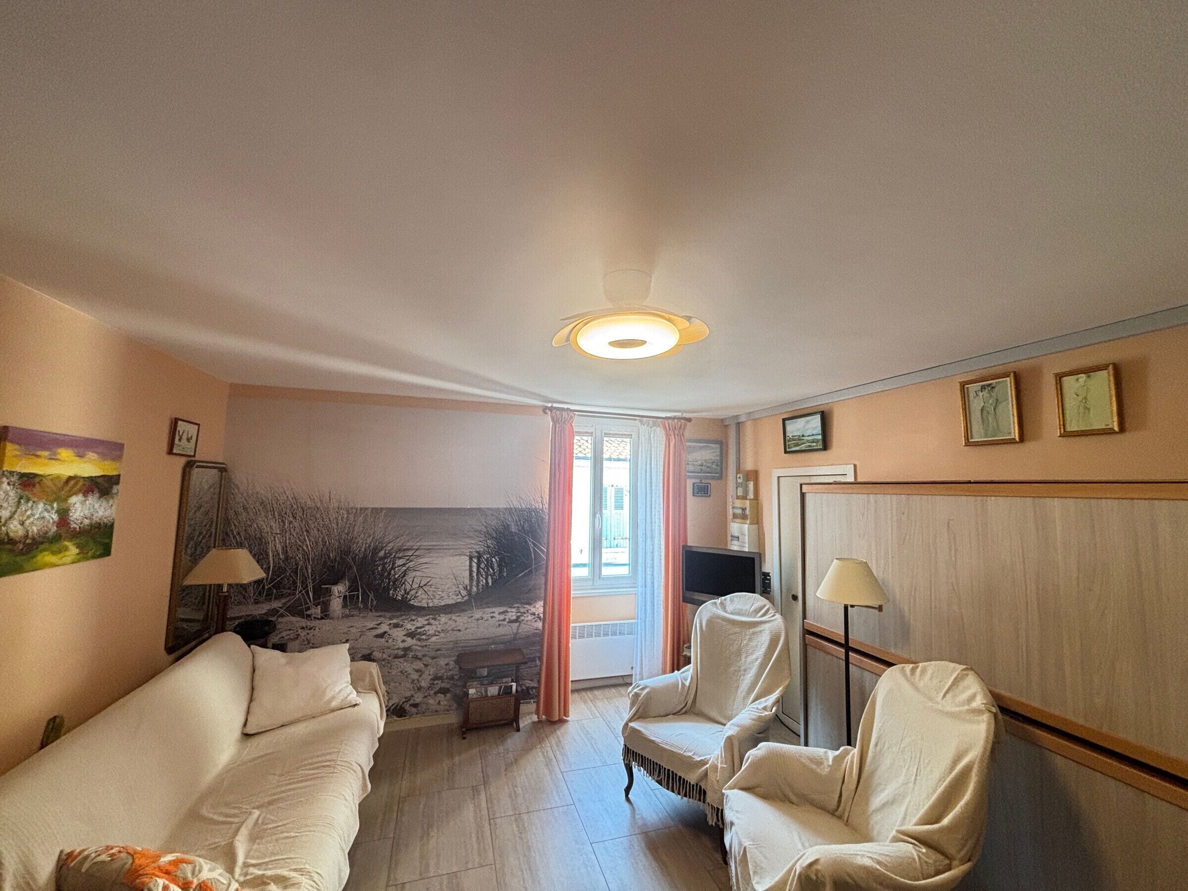 Una habitación con un sofá, dos sillones, un televisor y un cuadro en la pared.