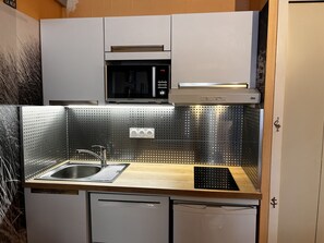 A compact kitchen with a stainless steel sink, a microwave, and a dishwasher.