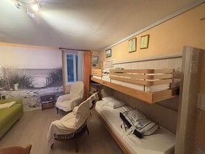 Camera d'albergo con letti a castello, una sedia, una scrivania e vista sulla spiaggia.