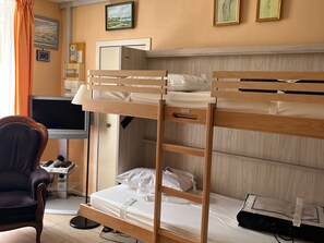 A bunk bed room with a desk, chair, television, and artwork on the walls.