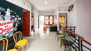A hallway with a welcome sign, chairs, a staircase, and a view into a living area. - Homestay Jogja dekat Ambarukmo by Simply Homy (Depok)
