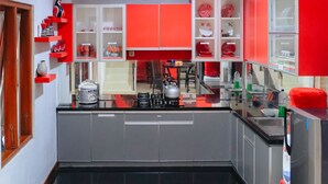 A modern kitchen with grey cabinets, red accents, and a black tiled floor. - Homestay Jogja dekat Ambarukmo by Simply Homy (Depok)