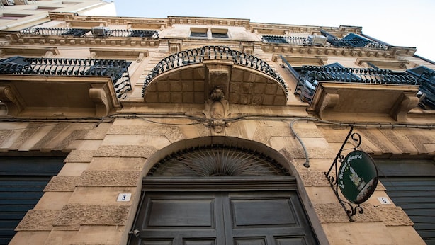 A building facade with a large arched entrance, a sign with a view of the city, and a number '8' on the wall. - Agatea a due passi dal Duomo by Wonderful Italy (Catania)