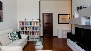 A living room with a white sofa, a bookshelf, a coffee table, and a television. - Agatea a due passi dal Duomo by Wonderful Italy (Catania)