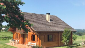 Una casa de madera con techo inclinado, una chimenea y un porche con sillas.