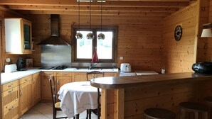 Cocina de cabaña de madera con mesa, sillas, estufa y ventana con vistas.