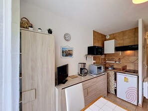 Una cocina compacta con microondas, cafetera y refrigerador.