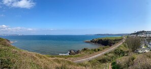 A coastal landscape with a railway track, a body of water, and a distant town. - Pool-garden-2br-parking-wifi-sleeps6 (Paignton)