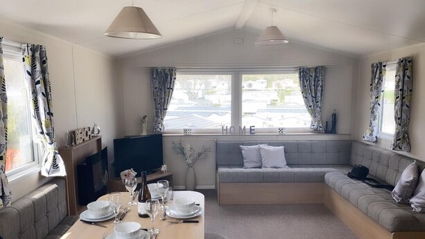 A cozy living room with a sofa, a TV, and a dining table set for two. - Pool-garden-2br-parking-wifi-sleeps6 (Paignton)