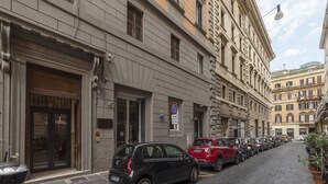 A narrow cobblestone street lined with parked cars and historic buildings with classical architecture. - GuestHost - Elegant 110 sqm apartment, which can accommodate up to 3 people, located on the fourth floor of a period building with lift (not suitable for the disabled). The property, in the Traffic Restricted Area (ZTL), is located in the heart of the hi (Roma)