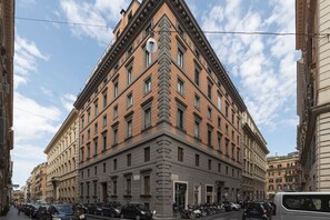 Un edificio en esquina con una entrada amplia y varias ventanas.