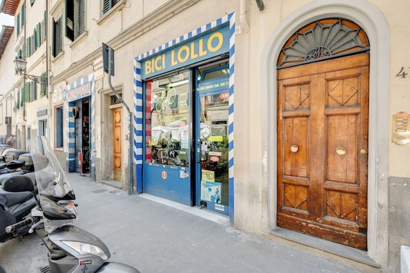 A storefront with a blue and white striped awning, a wooden door, and a scooter parked outside.