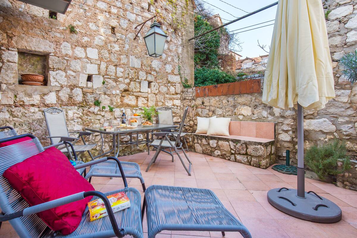 A stone-walled outdoor patio with wicker furniture, a table, and an umbrella.
