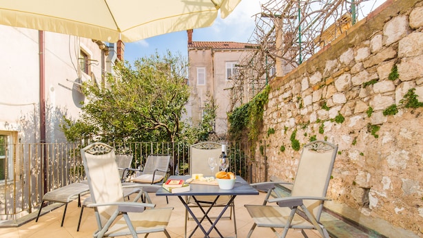 Eine Terrasse im Freien mit Tisch, Stühlen und einer Weinflasche.