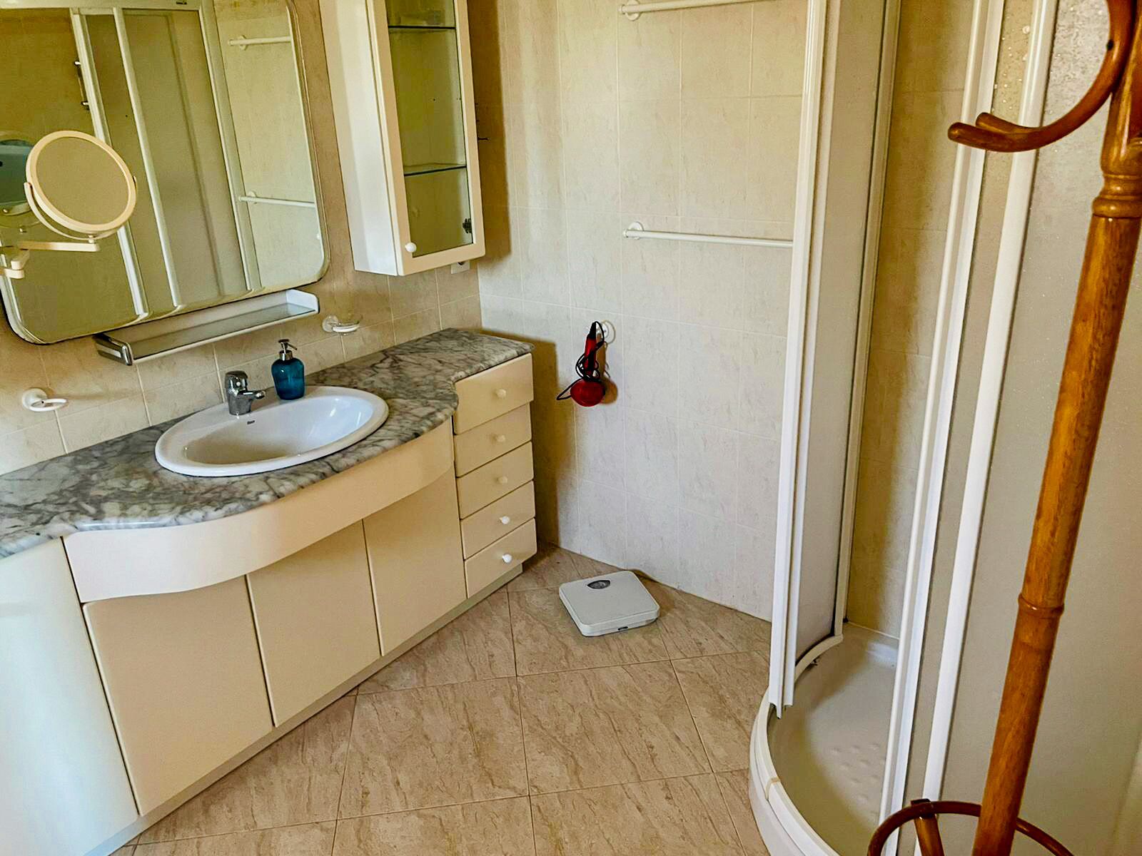 A bathroom with a white sink, a mirror, a towel rack, and a shower area.